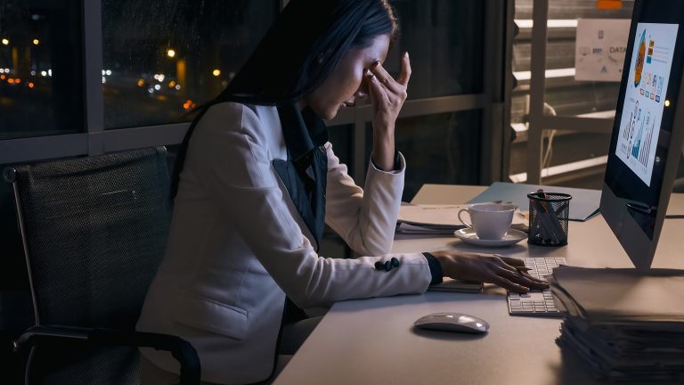 Stressed young Asian businesswoman working overtime at the office