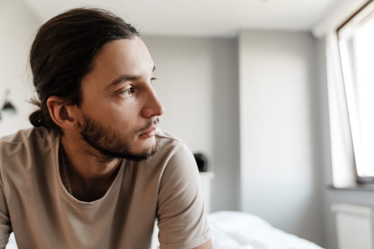 Young man in depression sitting on bed